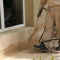 General pest control technician spraying exterior perimeter around a home in Rockford, IL
