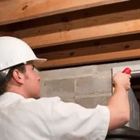 Termite inspection technician checking a basement wall and framing for termite activity in Rockford, IL