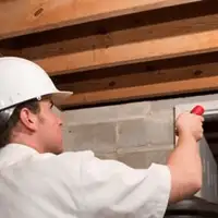 Termite inspection technician checking a basement wall and framing for termite activity in Rockford, IL